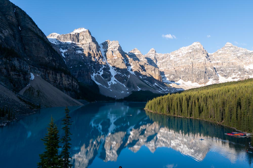 Sunrise light on the Ten Peaks reflected in the calm turquoise water of Moraine Lake.