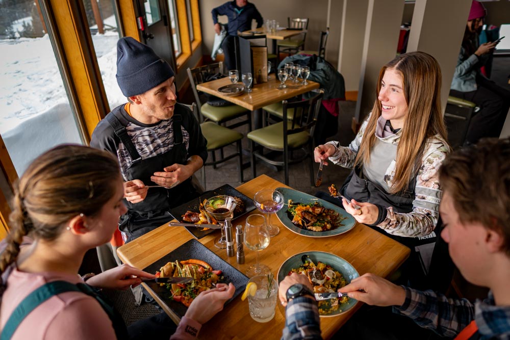 Original: Guests enjoy lunch inside Whitehorn Bistro, warm light on the table with plated dishes and winter views outside.